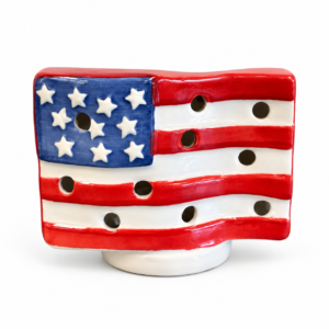 Red white and blue ceramic American flag candle holder with raised stars, stripes, and decorative openings