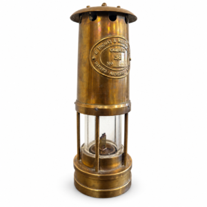 Vintage-style brass miner’s safety lantern with cylindrical metal body, glass chamber, and antique finish