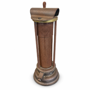 Vintage-style tall metal heater with cylindrical mesh body, round base, and aged bronze-brown finish.