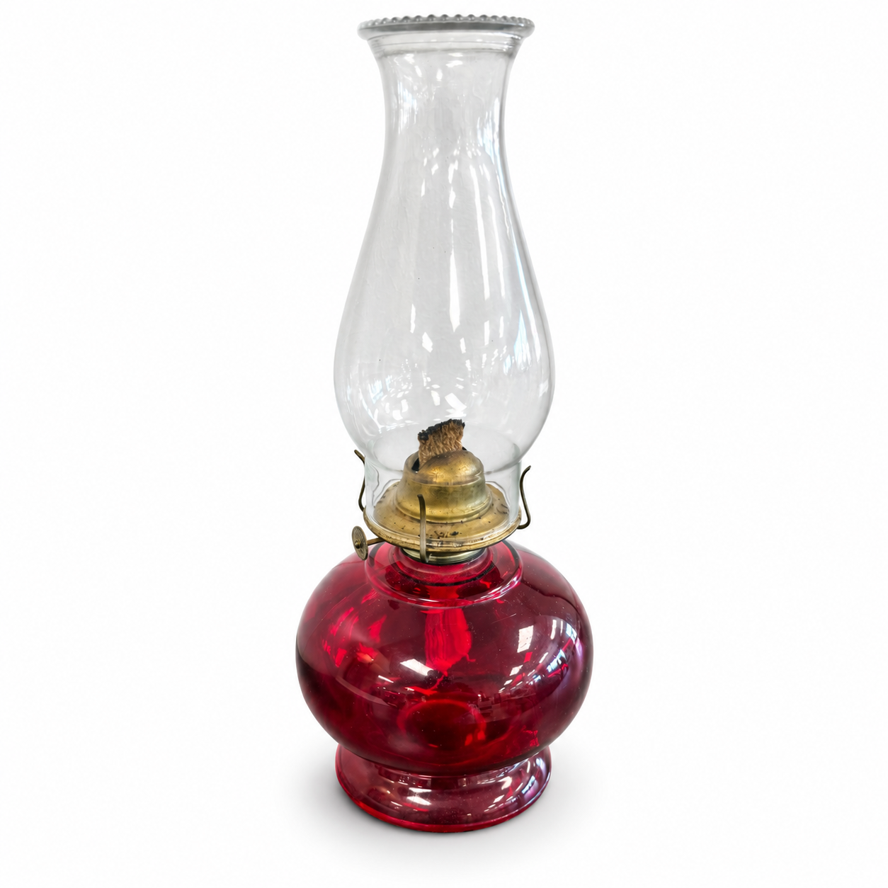 Vintage-style oil lamp with a deep red glass base, brass-tone burner, and tall clear glass chimney.