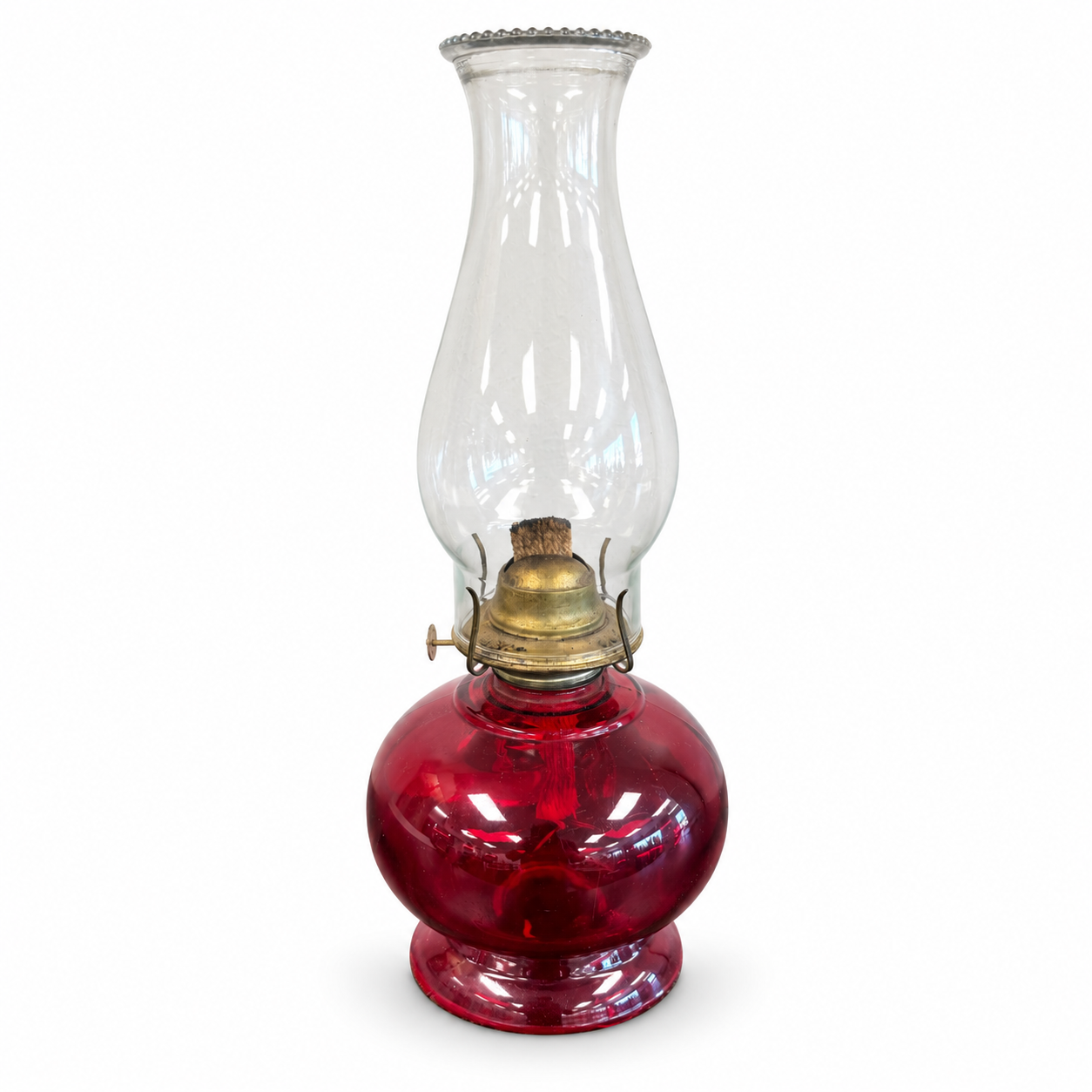 Vintage-style oil lamp with a deep red glass base, brass-tone burner, and tall clear glass chimney.